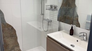 Un bagno moderno con doccia vetrata, un lavabo bianco con mobile in legno e uno specchio grande.