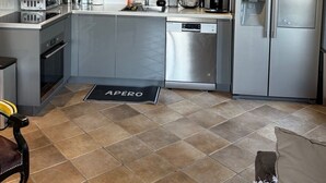 Una cucina moderna con elettrodomestici in acciaio inossidabile, lavastoviglie e macchina per il caffè.