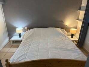 A bedroom with a bed, two bedside tables with lamps, a grey wall, and a tiled floor. - Beautiful Mazet in Pramousquier, Le Lavandou, with Terrace, 3 Bedrooms Sea View. (LE LAVANDOU)