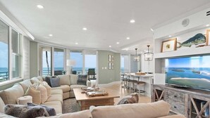 A spacious living room with a large television, comfortable seating, and a view of the ocean. - Beachfront 3BR/3BA condo with pool, WiFi, and heated outdoor pool. (Marco Island)