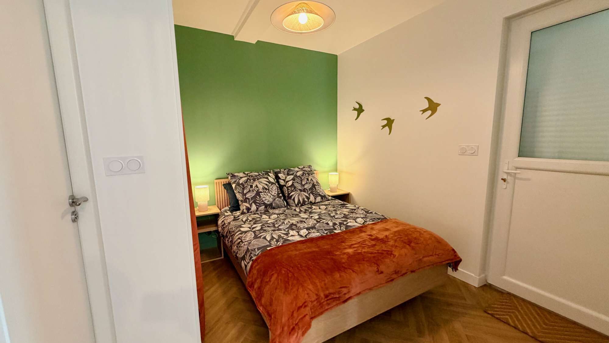 Une chambre à coucher avec un lit, une table de chevet, une lampe et une porte.