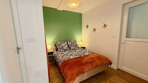 Une chambre à coucher avec un lit, une table de chevet, une lampe et une porte.