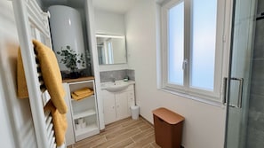 Une salle de bain moderne avec un meuble-lavabo blanc, un évier, un miroir, une fenêtre et un porte-serviettes.