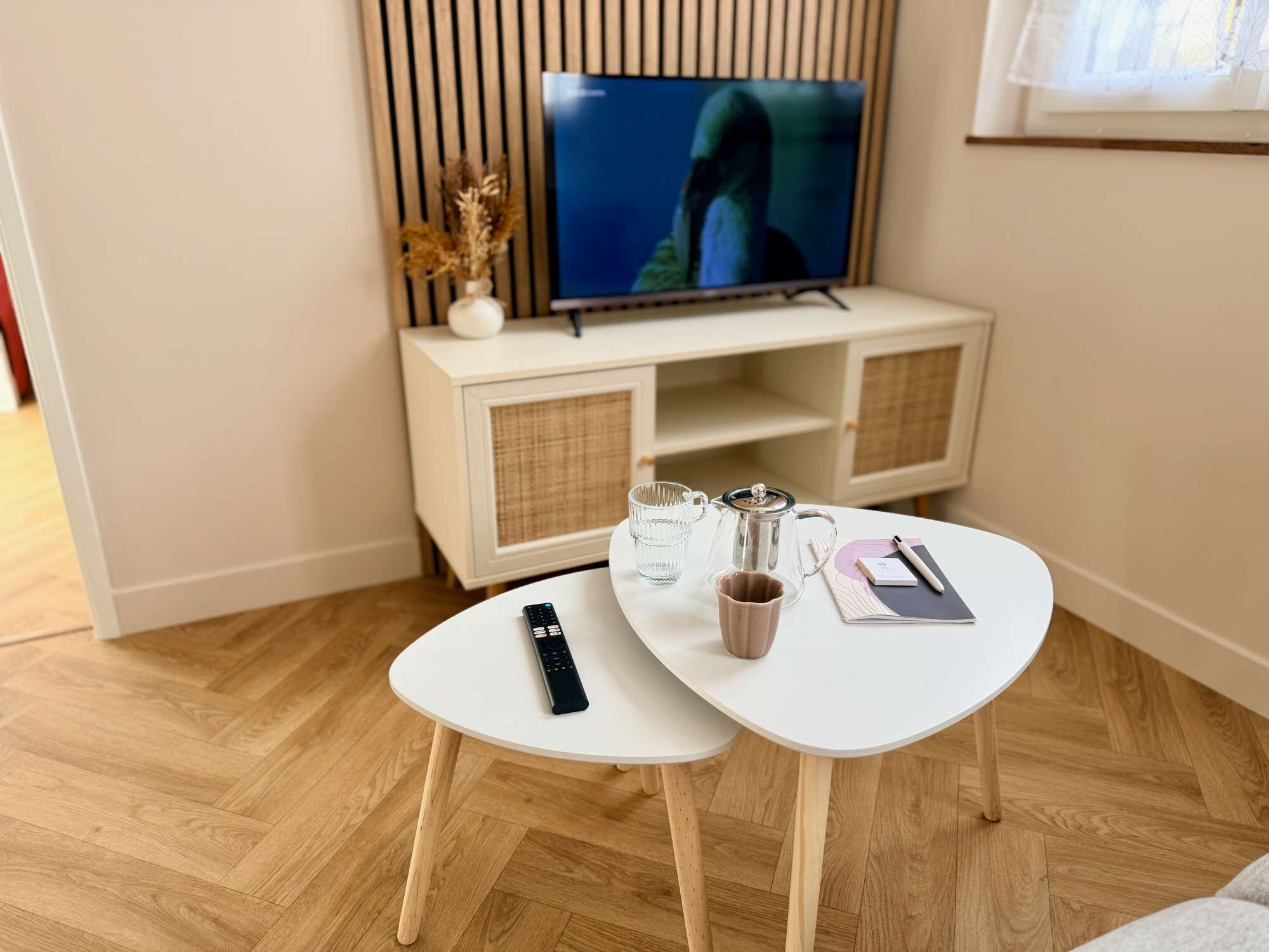Un salon moderne avec un téléviseur, une table basse, une télécommande et un carnet.