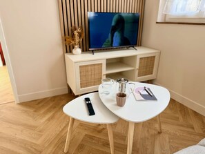 Un salon moderne avec un téléviseur, une table basse, une télécommande et un carnet.