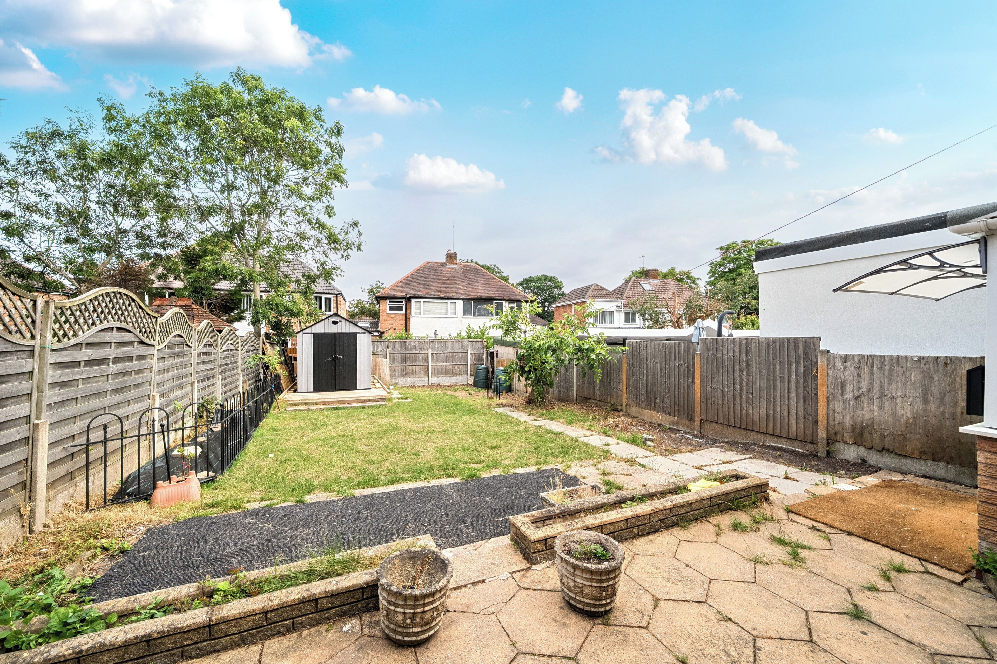 A backyard with a paved area, a small shed, and a wooden fence.