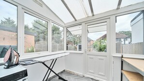 Una habitación con lavadora, tabla de planchar y un amplio ventanal con vistas al exterior.