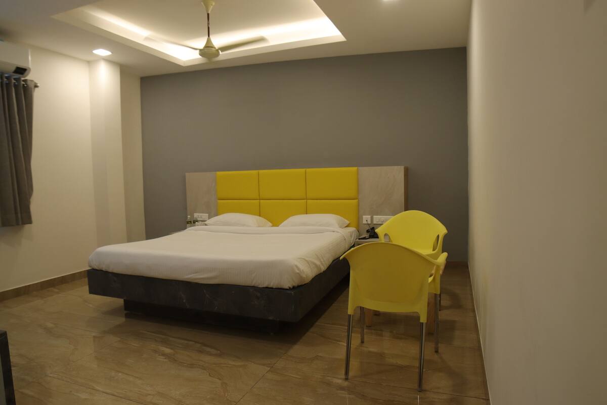 A modern bedroom with a bed, a ceiling fan, and a yellow chair.