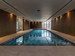 Ein moderner, überdachter Pool mit freier Sicht, geflieste Wände und einer Decke mit eingelassener Beleuchtung.