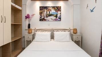 Een slaapkamer met een bed, twee nachtkastjes, een kledingkast en een schilderij aan de muur.