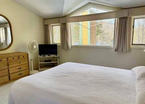 A bedroom with a bed, dresser, TV stand, and a window with curtains. - Cozy 3-bedroom condo with AC in Master Bedroom in scenic Waterville Valley NH (Waterville Valley)