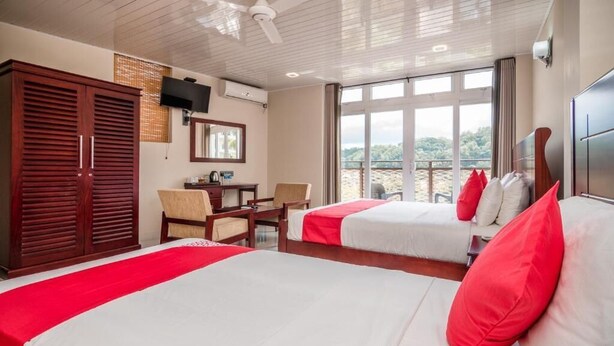 A hotel room with two beds, a desk, a chair, a wardrobe, and a large window with a view. - Jenora Hills - Kandy (Kandy)