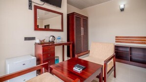 A room with a wooden desk, a chair, a television mounted on the wall, a wardrobe, and a small white appliance. - Jenora Hills - Kandy (Kandy)