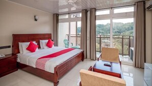 A hotel room with a large bed, a desk, a chair, and a balcony with a view. - Jenora Hills - Kandy (Kandy)
