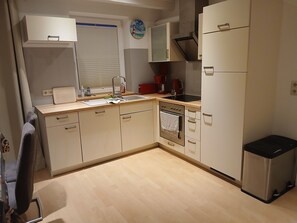 Eine kleine Küche mit Spüle, Backofen und Mülleimer.
