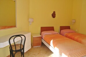 Une chambre avec un lit simple, un bureau, une chaise et deux lampes de chevet.