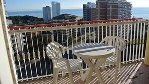 A balcony with a white railing, two white plastic chairs, and a small round table. - Practical flat with pool just 100m from the beach (Lignano Sabbiadoro)