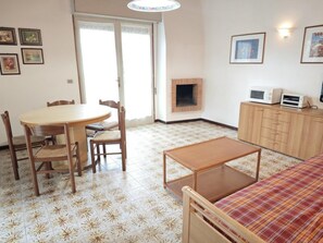 Huone, jossa on ruokapöytä, tuoleja, sohva, takka, mikroaaltouuni ja kaappi.