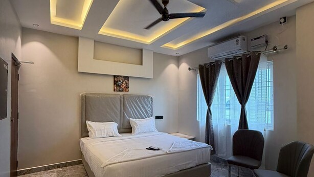 A modern bedroom with a bed, ceiling fan, air conditioning unit, and a view of the outdoors. - Sasikala Residency  (Madurantakam)