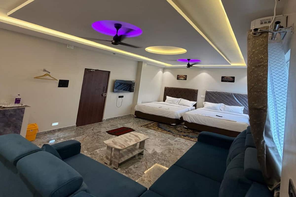 Habitación de hotel con dos camas, un sofá, un televisor y un ventilador de techo.