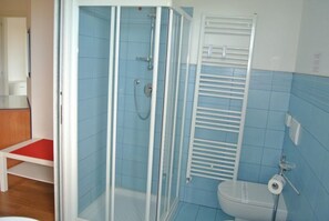 Een badkamer met een douchecabine van glas, een wit toilet en een handdoekrek.