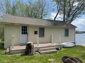 A small, single-story cabin with a front door, a window, and a deck.