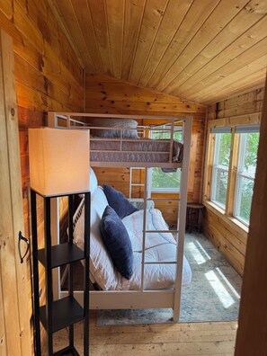 A bunk bed with a bedside table and a window.