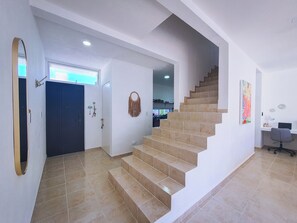 Ein modernes Interieur mit einer geschwungenen Treppe, einem Schreibtisch mit Stuhl und einer Tür mit dekorativen Elementen.