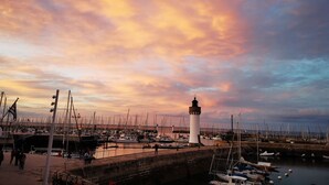 A harbor with a lighthouse, boats, and a pier with people and bicycles. - The roch annex (Saint-Pierre-Quiberon)