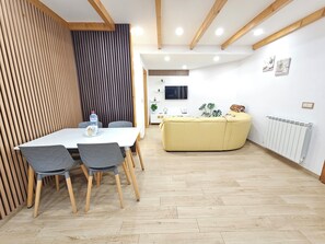 Un intérieur moderne comprenant un coin repas, un canapé, un téléviseur et un radiateur.