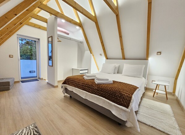 Une chambre à coucher avec un lit, une table de chevet, une chaise et une vue sur l’extérieur.