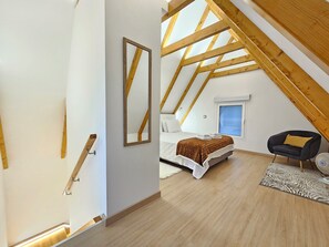 Une chambre à coucher avec un lit, une fenêtre, une chaise et une structure de plafond en bois.