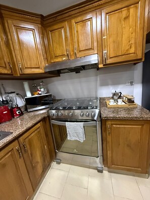 A kitchen with wooden cabinets, a stainless steel stove, a blender, and a coffee maker. - Town house Vilas Bavaro (Punta Cana)