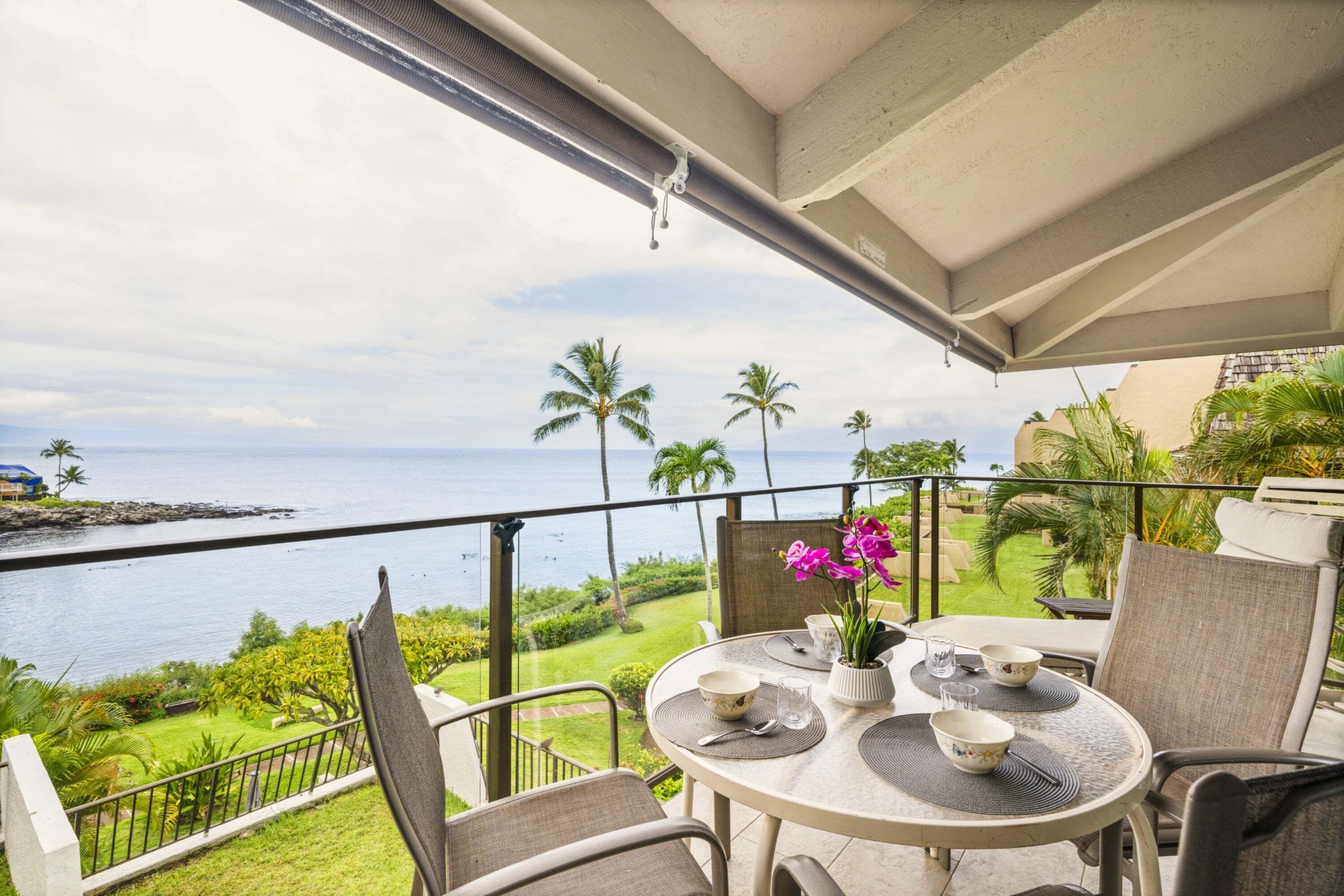 A balcony with a table set for dining, overlooking a body of water and greenery.
