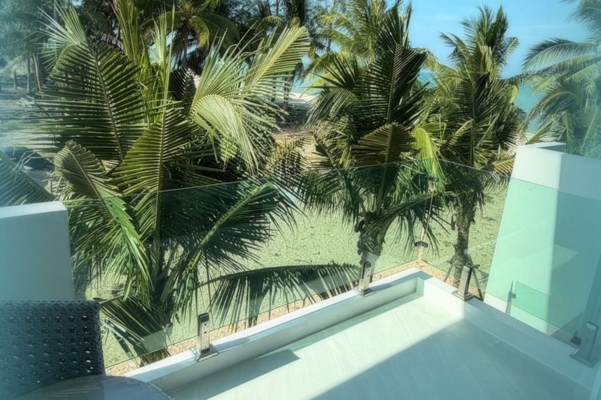 Un balcón con vistas a palmeras y un cielo despejado.