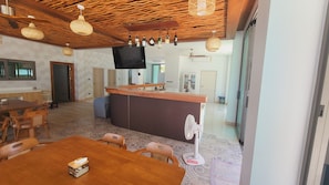 Una cocina moderna con encimera de madera, un comedor con mesa y sillas de madera, e iluminación tejida en el techo.