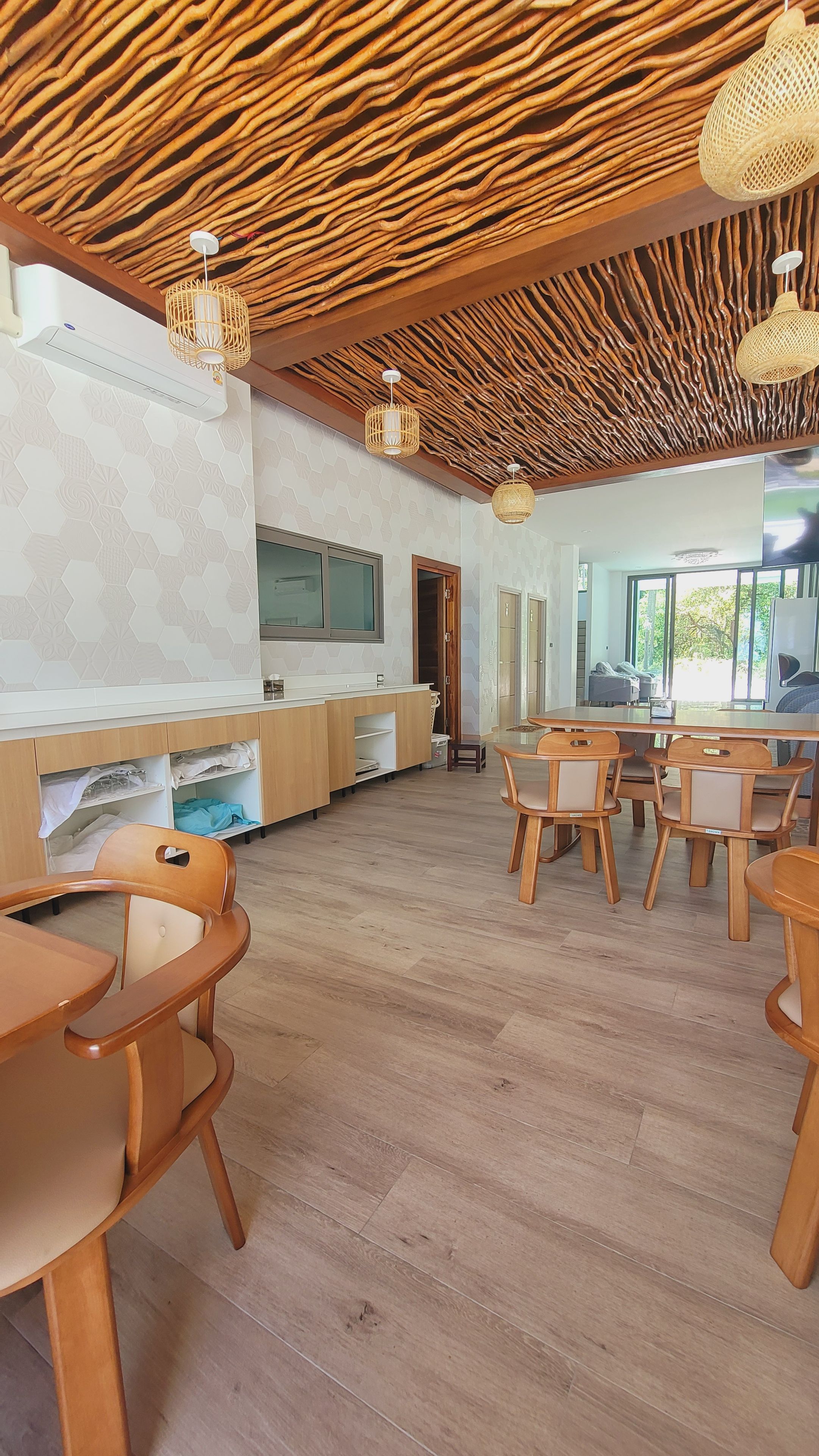 A spacious room with a wooden ceiling, a kitchen area, and seating arrangements.