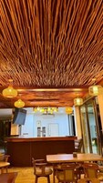 Interior de restaurante con techo de madera, zona de bar y mesas.