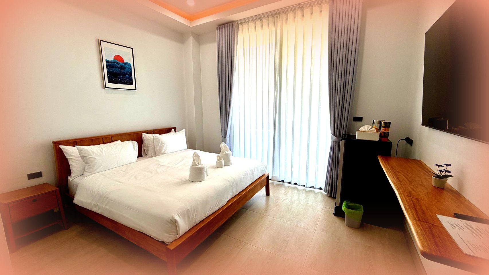A hotel room with a bed, a desk, a television, and a window with curtains.