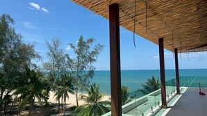 Vista sulla spiaggia con una zona ombreggiata, palme e una visuale aperta sull'oceano.