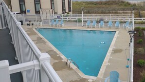 A pool area with a view of the beach, surrounded by white railings and blue chairs. - Just listed for rent! Oceanview condo in an oceanfront building with a pool, elevator and assigned parking (Ocean City)