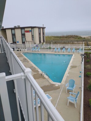 A pool area with a view of the beach, surrounded by white railings and blue chairs. - Just listed for rent! Oceanview condo in an oceanfront building with a pool, elevator and assigned parking (Ocean City)