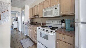 A kitchen with wooden cabinets, a white stove, a microwave, and a coffee maker. - Just listed for rent! Oceanview condo in an oceanfront building with a pool, elevator and assigned parking (Ocean City)