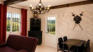 Ein Essbereich mit Tisch und Stühlen, einer Deckenleuchte, einem Wappen an der Wand und Blick durch das Fenster.