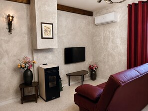 A living room with a fireplace, a flat-screen TV, a red sofa, and two vases with flowers.