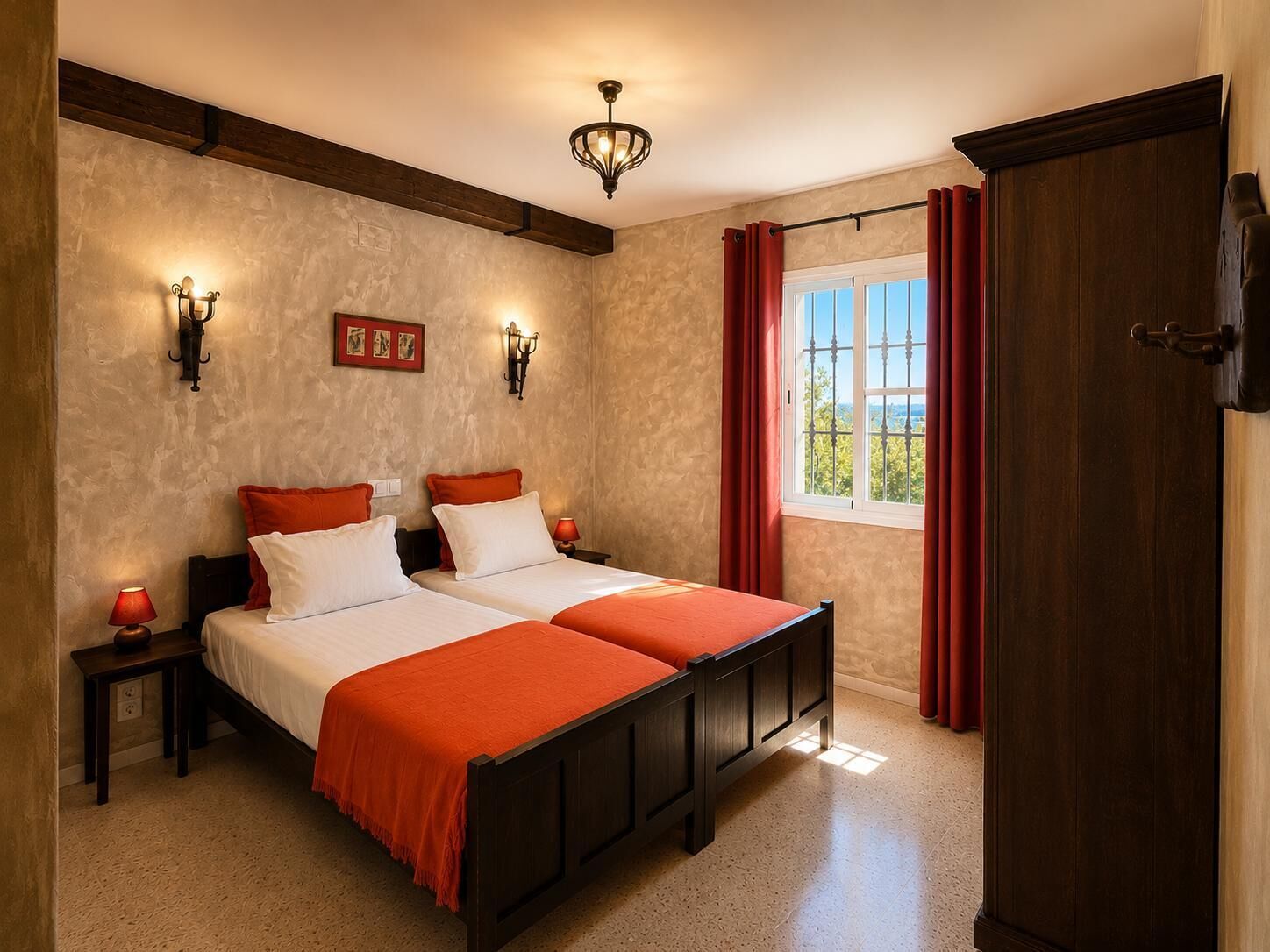 A bedroom with two beds, a window with curtains, wall sconces, and a wooden ceiling beam.. Posada Aurora | Holiday home with swimming pool, donkeys & horses near Córdoba