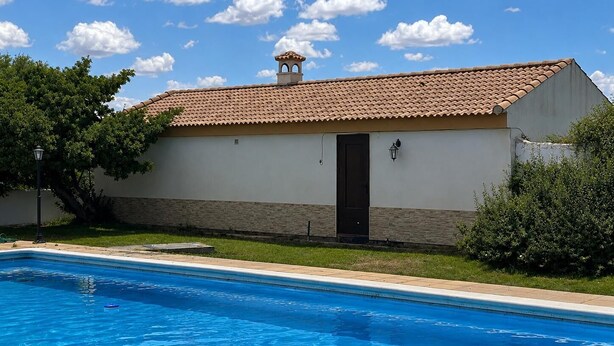 A building with a swimming pool, a tiled roof, and a door.