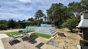En have med swimmingpool, udendørs møbler og grillplads.