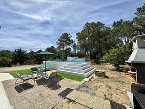 Ein Garten mit Swimmingpool, Sitzgelegenheit im Freien und Grillplatz.