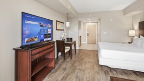 Hotellihuone, jossa on televisio, sänky, työpöytä ja tuoli.